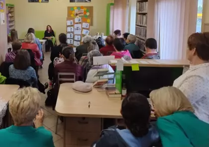 Czytelnicy siedzą w bibliotece i słuchają Pani Magdaleny Wala.