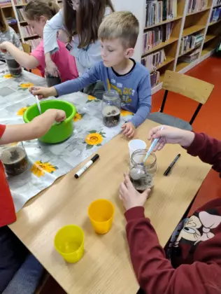 Dzieci sypią ziemię do słoików.