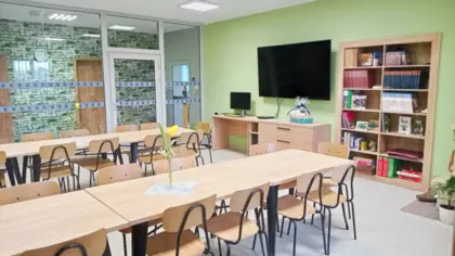 Czytelnia. Na środku stoją stoliki z krzesełkami, pod ścianą stoi biurko a na ścianie wisi telewizor.