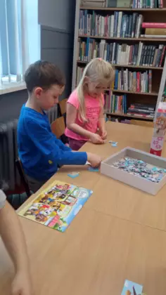 Chłopczyk i dziewczynka układają puzzle.
