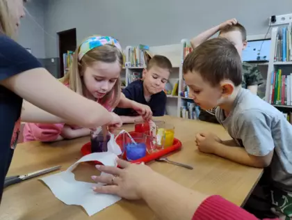 Dzieci tworzą tęczę z papieru i kolorowego płynu.