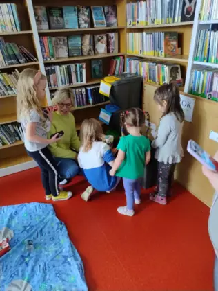 Przedszkolaki segregują śmieci do odpowiednich pojemników.