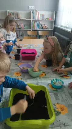 Dzieci sadzą rośliny do doniczek.