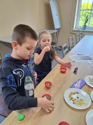 Chłopczyk i dziewczynka tworzą czekoladowe batoniki w silikonowych foremkach.