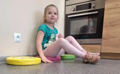 Dziewczynka na podstawie baśni Księżniczka na ziarnku grochu siada na poduszkach i szuka pod którą jest schowany cukierek.