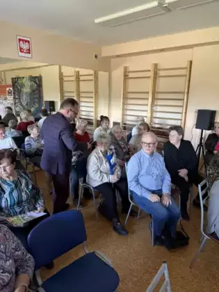 Edward Przebieracz rozdaje książki seniorom.