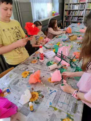 Dzieci wykonują kwiaty z bibuły.