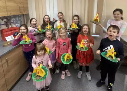 Wspólne zdjęcie po zajęciach bibliotecznych. Dzieci trzymają w rękach papierowe kurki.