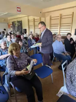 Edward Przebieracz rozdaje książki seniorom.