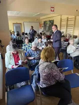 Edward Przebieracz rozdaje książki seniorom.