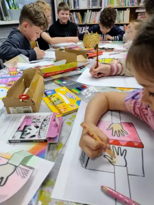 Dzieci na zajęciach kolorują kredkami.