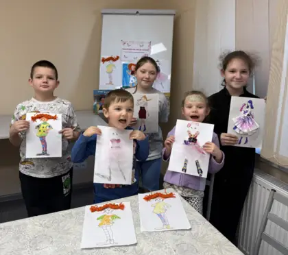 Pięć uśmiechniętych dzieci trzyma w rękach swoje prace plastyczne.