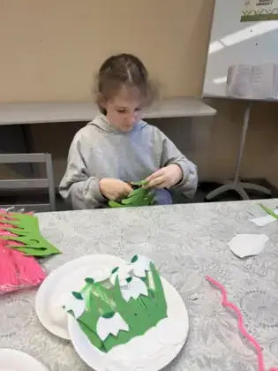 Dziewczynka wycina paski z zielonego papieru.