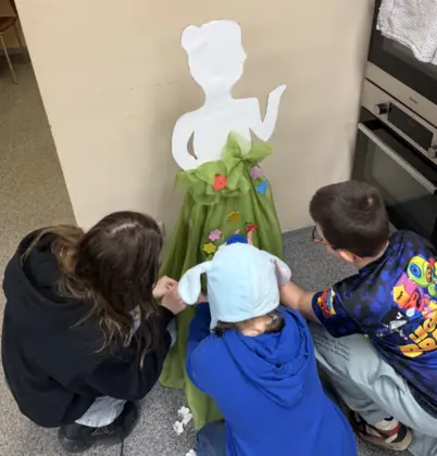 Troje dzieci przykleja ozdoby do sukni pani wiosny.