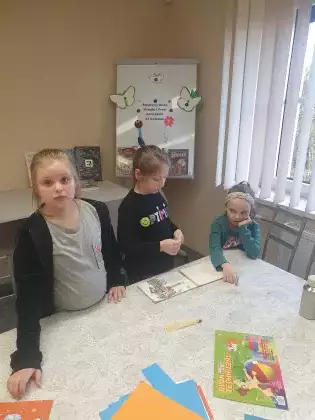 Uczestniczki na zajęciach plastycznych w bibliotece sklejają zniszczoną książeczkę.