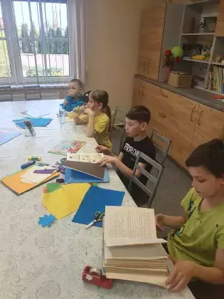 Chłopcy siedzą przy stole na zajęciach i oglądają książki.