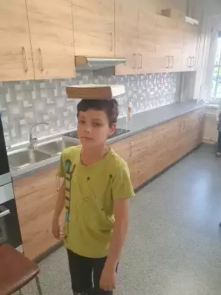 Chłopiec idzie z książką na głowie.