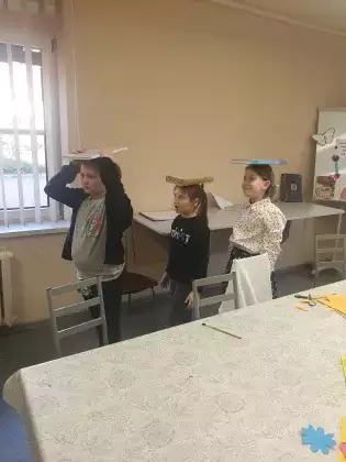 Dziewczyny maszerują z książką na głowie.