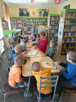 Dzieci w bibliotece oglądają książeczki.