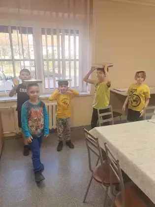 Dzieci na zajęciach ruchowych idą z książką na głowie.