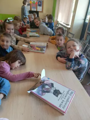 Dzieci w bibliotece oglądają książki.