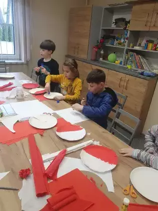 Chłopcy wyklejają biało-czerwoną flagę.