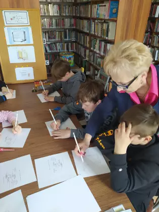 W bibliotece uczestnicy zajęć tworzą mini książeczki.