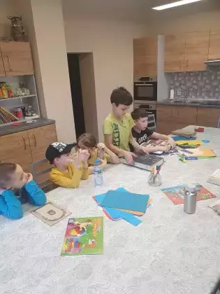 Chłopcy przy wspólnym stole oglądają książki.