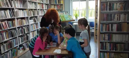 Dzieci wraz z bibliotekarką rozwiązują krzyżówkę.