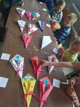 Na stole leżą prezenty na dzień mamy wykonane przez dzieci z kolorowego papieru.