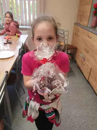 Dziewczynka trzyma w rękach słodki prezent na Dzień Mamy.