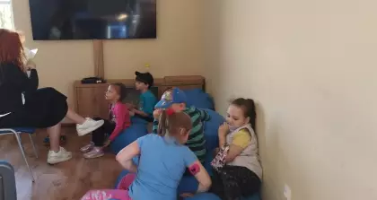 Dzieci słuchają książki czytanej przez bibliotekarkę.