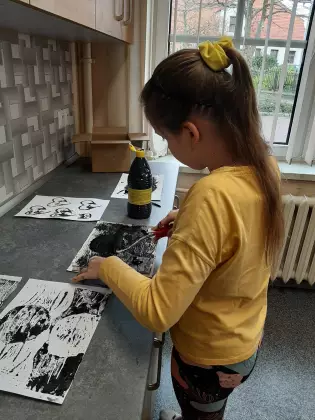 Dziewczynka maluje obraz farbą.