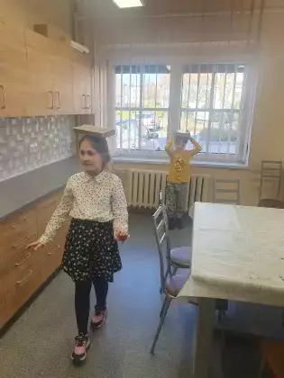 Dziewczynka i chłopiec idą z książką na głowie.