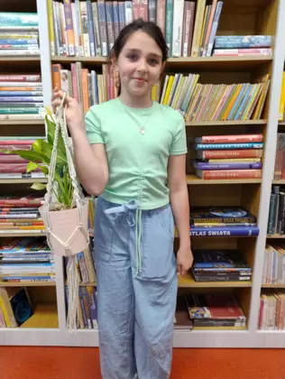 Dziewczynka trzyma w ręce wypleciony kwietnik dla mamy.