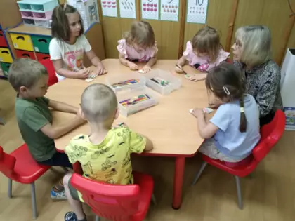 Przedszkolaki kolorują kwiatki dla mamy.