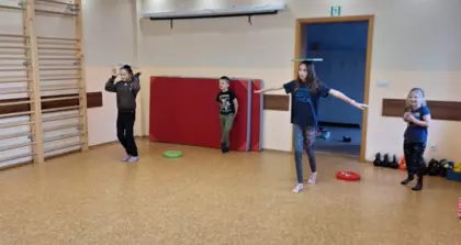 Zabawy na sali sportowej z książką  na głowie.