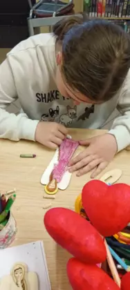 Uczestniczka koloruje drewnianego anioła.