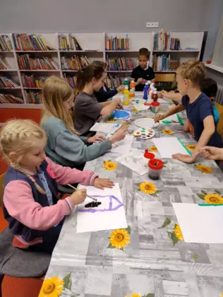 Uczestnicy zajęć malują farbami obrazy .