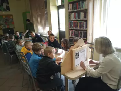 Przedszkolaki słuchają teatrzyku kamishibai.