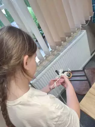 Uczestniczka plecie ze sznurka kwietnik dla mamy