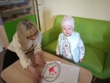 Dziewczynka ogląda książeczkę z bibliotekarką.