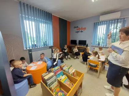 Dzieci słuchają o czym opowiada im pani bibliotekarka.
