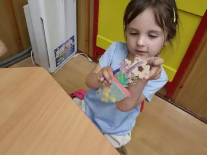 Dziewczynka pokazuje kwiatek pomalowany dla mamy.