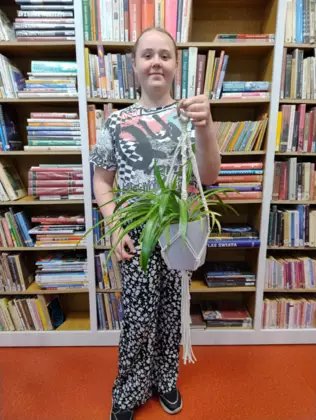 Dziewczynka trzyma w ręce wypleciony kwietnik dla mamy.