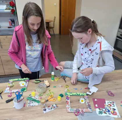 Dziewczyny metodą decoupage oklejają tekturowe ramki na zdjęcia.