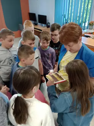 Pani bibliotekarka częstuje dzieci czekoladkami.