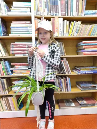 Dziewczynka trzyma w ręce wypleciony kwietnik dla mamy.