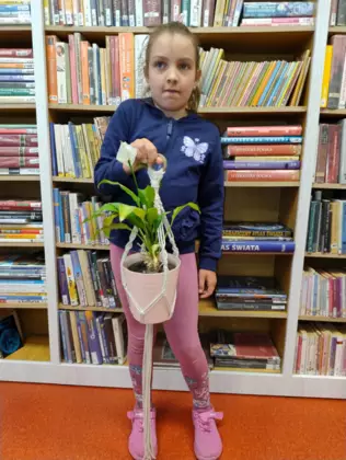 Dziewczynka trzyma w ręce wypleciony kwietnik dla mamy.