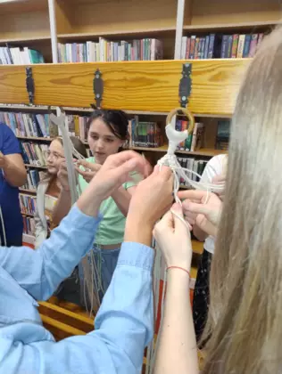 Uczestnicy wyplatają sznurki tworząc kwietnik.